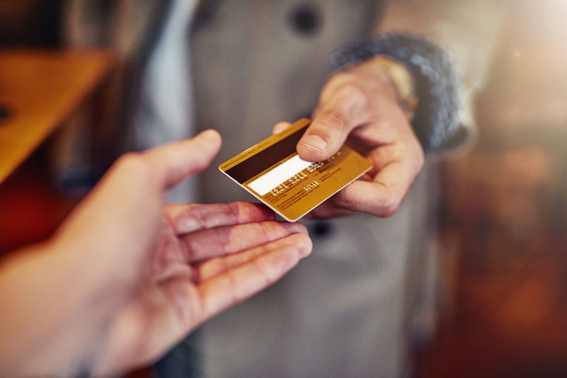 Two hands are reaching out exchanging a payment card