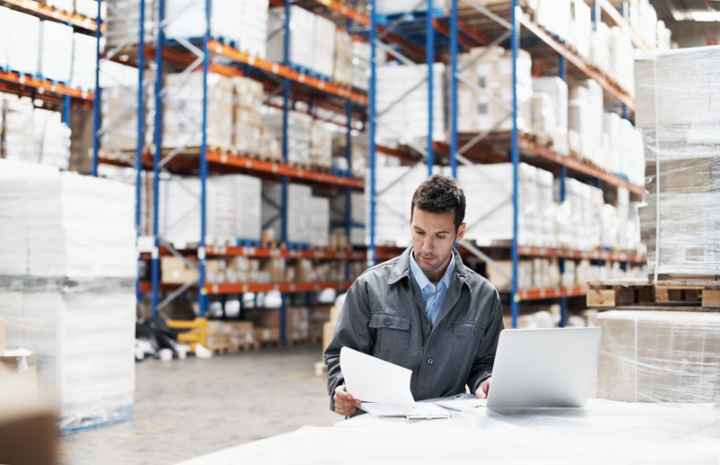 a man sits and completes paperwork in a large warehouse